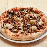 Pizza Végétarienne Artichauts & Champignons Gourmet Pizza végétarienne artisanale, bien cuite, garnie de champignons, d'artichauts et de poivrons rouges sur une croûte dorée, servie sur une assiette blanche.