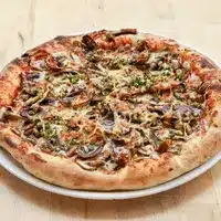Délicieuse Pizza Champignons : Croûte Dorée et Rustique Pizza rustique aux champignons et herbes vertes, bien cuite avec une croûte dorée et boursouflée, présentée sur une assiette blanche.