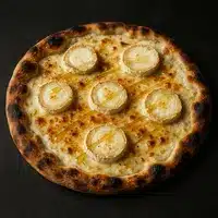 Pizza Chèvre Miel : Délice Croustillant au Fromage Chaud Pizza gourmande avec base de fromage crémeux, cinq ronds de chèvre chaud et un filet de miel doré, croûte bien dorée et légèrement noircie.