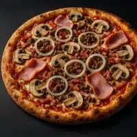 Pizza Gourmande Viande, Champignons et Jambon Pizza garnie de viande hachée, tranches de jambon, champignons émincés et rondelles d'oignon blanc sur une croûte dorée, sur fond noir.