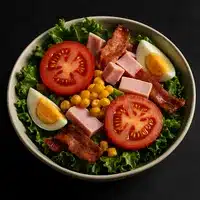 Salade Composée Repas : Tomates, Jambon, Bacon & Œuf Salade composée garnie de laitue, tranches de tomates, dés de jambon, morceaux de bacon croustillants, maïs et œufs durs coupés en deux.